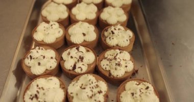 Metal tepside çikolata parçacıkları serpiştirilmiş mini tartlar. Profesyonel bir şekercinin işi.