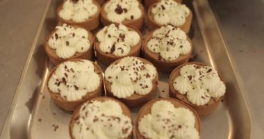 Metal tepside çikolata parçacıkları serpiştirilmiş mini tartlar. Profesyonel bir şekercinin işi.