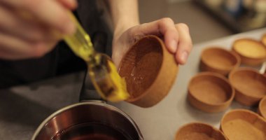 Şekerlemecinin ellerine yakın plan fırçayla tart sürerken. Profesyonel bir pastacı tarafından tartların hazırlanması.