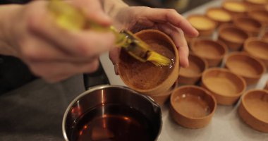 Şekerlemecinin ellerine yakın plan fırçayla tart sürerken. Profesyonel bir pastacı tarafından tartların hazırlanması.