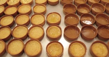 Çok sayıda mini tart, bir hamur fırçası yardımıyla onları elma şurubuyla hamile bırakma sürecinde profesyonel bir hamur işi masasına dizilir..