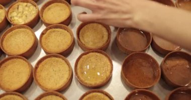 Çok sayıda mini tart, bir hamur fırçası yardımıyla onları elma şurubuyla hamile bırakma sürecinde profesyonel bir hamur işi masasına dizilir..