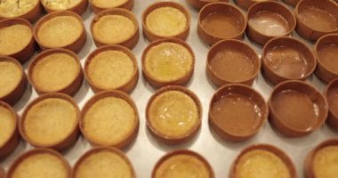 Çok sayıda mini tart, bir hamur fırçası yardımıyla onları elma şurubuyla hamile bırakma sürecinde profesyonel bir hamur işi masasına dizilir..