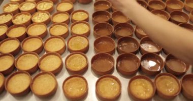 Çok sayıda mini tart, bir hamur fırçası yardımıyla onları elma şurubuyla hamile bırakma sürecinde profesyonel bir hamur işi masasına dizilir..