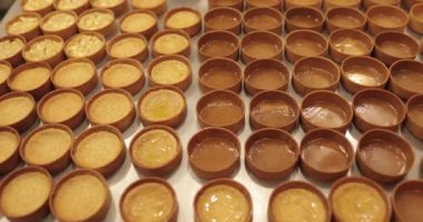 Çok sayıda mini tart, bir hamur fırçası yardımıyla onları elma şurubuyla hamile bırakma sürecinde profesyonel bir hamur işi masasına dizilir..