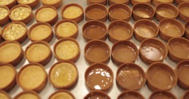 Çok sayıda mini tart, bir hamur fırçası yardımıyla onları elma şurubuyla hamile bırakma sürecinde profesyonel bir hamur işi masasına dizilir..