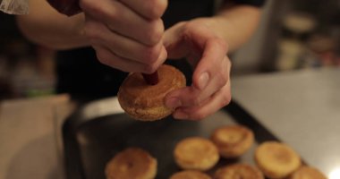 Şekerleme makinesi pasta şırıngası kullanarak ekini kremayla dolduruyor. Pişirme şırıngası olan kadın elleri.