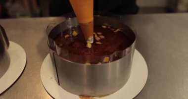 Çikolatalı turtanın mutfak şırıngası ile dekorasyonu üzerinde çalışan bir kadın eli..
