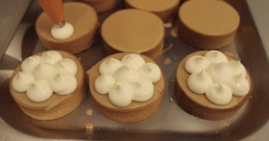 Aşçılık şırıngası kullanarak tartlara krema süslemek. Profesyonel şekerleme mutfağı. Profesyonel bir şekerci tarafından tartların toplu dekorasyonu.