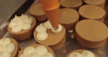 Aşçılık şırıngası kullanarak tartlara krema süslemek. Profesyonel şekerleme mutfağı. Profesyonel bir şekerci tarafından tartların toplu dekorasyonu.