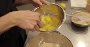 Profesyonel bir pasta şefi kadın yumurtaları karıştırır ve hamuru hazırlamak için büyük bir kaseye koyar.