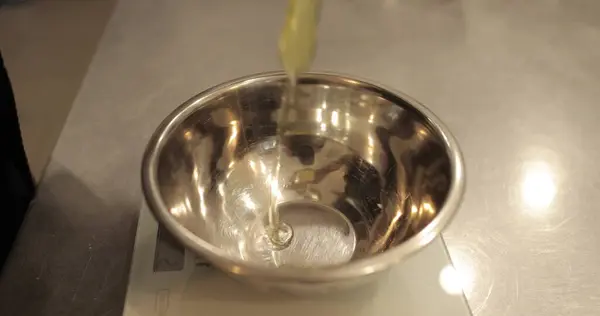 Çiğ tavuk yumurtaları, profesyonel bir pasta mutfağının masasında metal bir kaseye kırılır..
