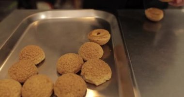 Şekerlemecinin muhallebi ile doldurmak için hazırladığı profiteroller bir tabağa konur. Bir şekerlemecinin kadın elleri eklerlerle başlar..