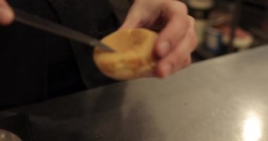 Şekerlemecinin muhallebi ile doldurmak için hazırladığı profiteroller bir tabağa konur. Bir şekerlemecinin kadın elleri eklerlerle başlar..