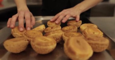 Şekerlemecinin muhallebi ile doldurmak için hazırladığı profiteroller bir tabağa konur. Bir şekerlemecinin kadın elleri eklerlerle başlar..