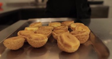 Şekerlemecinin muhallebi ile doldurmak için hazırladığı profiteroller bir tabağa konur. Bir şekerlemecinin kadın elleri eklerlerle başlar..