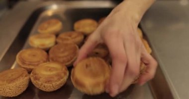 Şekerlemecinin muhallebi ile doldurmak için hazırladığı profiteroller bir tabağa konur. Bir şekerlemecinin kadın elleri eklerlerle başlar..