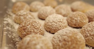 Pudra şekeri serpiştirilmiş hazır kekler profesyonel bir pastanenin metal tepsisinde sıraya dizilmiştir..