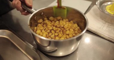 Elmaların şekerlemeleri doldurmak için hazırlanması. Bir tencerede doğranmış elmaları karıştırmak ve ısıtırken karıştırmak. Turtalar için dolgu.