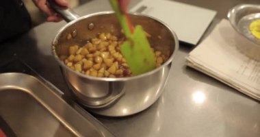 Elmaların şekerlemeleri doldurmak için hazırlanması. Bir tencerede doğranmış elmaları karıştırmak ve ısıtırken karıştırmak. Turtalar için dolgu.