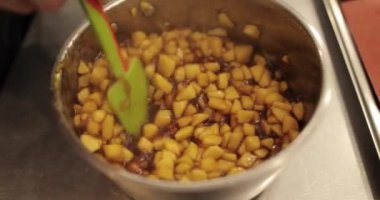 Elmaların şekerlemeleri doldurmak için hazırlanması. Bir tencerede doğranmış elmaları karıştırmak ve ısıtırken karıştırmak. Turtalar için dolgu.