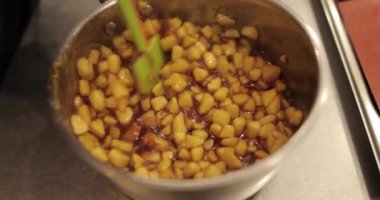 Elmaların şekerlemeleri doldurmak için hazırlanması. Bir tencerede doğranmış elmaları karıştırmak ve ısıtırken karıştırmak. Turtalar için dolgu.