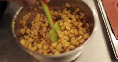 Elmaların şekerlemeleri doldurmak için hazırlanması. Bir tencerede doğranmış elmaları karıştırmak ve ısıtırken karıştırmak. Turtalar için dolgu.