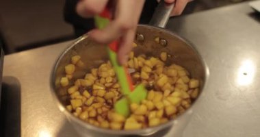 Elmaların şekerlemeleri doldurmak için hazırlanması. Bir tencerede doğranmış elmaları karıştırmak ve ısıtırken karıştırmak. Turtalar için dolgu.