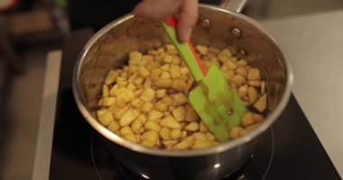 Elmaların şekerlemeleri doldurmak için hazırlanması. Bir tencerede doğranmış elmaları karıştırmak ve ısıtırken karıştırmak. Turtalar için dolgu.