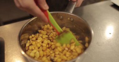 Elmaların şekerlemeleri doldurmak için hazırlanması. Bir tencerede doğranmış elmaları karıştırmak ve ısıtırken karıştırmak. Turtalar için dolgu.