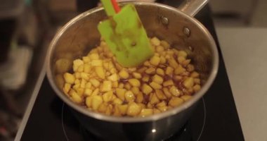 Elmaların şekerlemeleri doldurmak için hazırlanması. Bir tencerede doğranmış elmaları karıştırmak ve ısıtırken karıştırmak. Turtalar için dolgu.