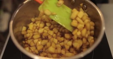 Elmaların şekerlemeleri doldurmak için hazırlanması. Bir tencerede doğranmış elmaları karıştırmak ve ısıtırken karıştırmak. Turtalar için dolgu.