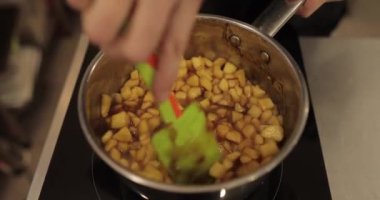 Elmaların şekerlemeleri doldurmak için hazırlanması. Bir tencerede doğranmış elmaları karıştırmak ve ısıtırken karıştırmak. Turtalar için dolgu.