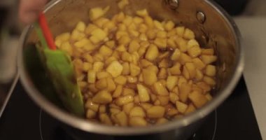 Elmaların şekerlemeleri doldurmak için hazırlanması. Bir tencerede doğranmış elmaları karıştırmak ve ısıtırken karıştırmak. Turtalar için dolgu.