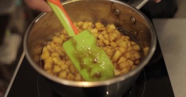 Elmaların şekerlemeleri doldurmak için hazırlanması. Bir tencerede doğranmış elmaları karıştırmak ve ısıtırken karıştırmak. Turtalar için dolgu.