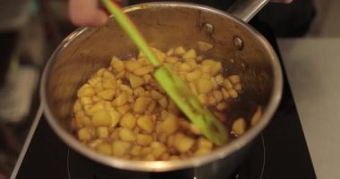 Elmaların şekerlemeleri doldurmak için hazırlanması. Bir tencerede doğranmış elmaları karıştırmak ve ısıtırken karıştırmak. Turtalar için dolgu.