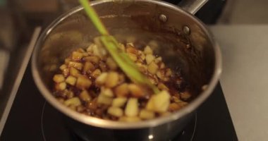 Elmaların şekerlemeleri doldurmak için hazırlanması. Bir tencerede doğranmış elmaları karıştırmak ve ısıtırken karıştırmak. Turtalar için dolgu.