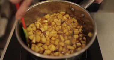 Elmaların şekerlemeleri doldurmak için hazırlanması. Bir tencerede doğranmış elmaları karıştırmak ve ısıtırken karıştırmak. Turtalar için dolgu.