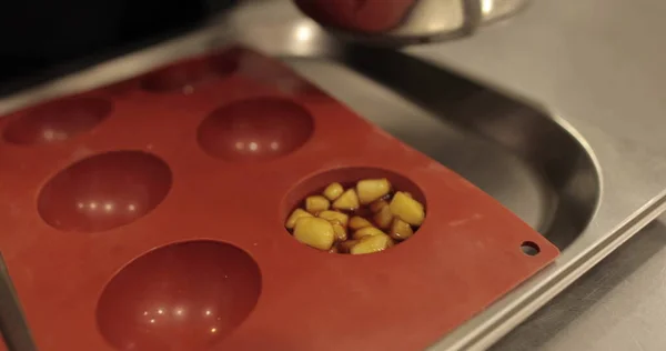 Preparation of apple desserts in a silicone baking tray. Filling a silicone tray with diced apples during the work of a professional confectioner.
