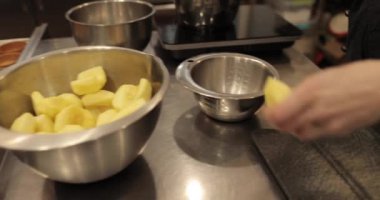 Profesyonel bir pastanede elma tatlısı yapmak için elmaları küp küp kesen kadın ellerine yakın plan..