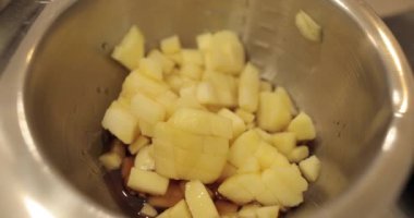 Profesyonel bir pasta mutfağında elma tatlısı hazırlarken ocakta elmalı metal bir tencere ısıtılır.