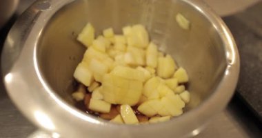 Profesyonel bir pasta mutfağında elma tatlısı hazırlarken ocakta elmalı metal bir tencere ısıtılır.