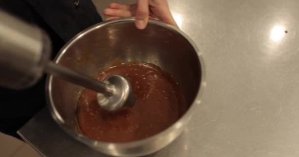 用搅拌机搅拌巧克力慕斯 用浸渍式搅拌机搅拌 将搅拌机放在专业厨房的贝塔碗中进行特写 — 图库视频影像