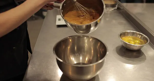 Mutfaktaki bir pasta şefi bir tencereden bir klozete çikolatalı mus döküyor. Aşçı çikolata jölelerini döker. Tatlıları yapma süreci