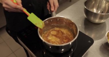 Tatlı hazırlarken sobanın üstünde silikon spatulayla çikolatalı mus karıştırmak.