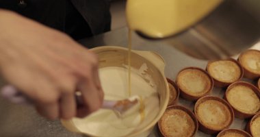 Bir pasta şefi tatlı karışımını bir kaseye koyar. Pasta yapma süreci yakın plan.