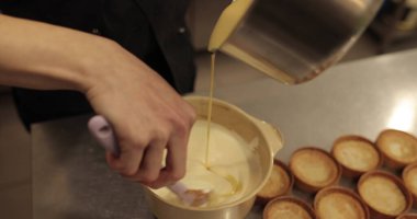 Bir pasta şefi tatlı karışımını bir kaseye koyar. Pasta yapma süreci yakın plan.