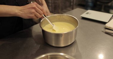 Bir pasta şefi tatlı karışımını bir kaseye koyar. Pasta yapma süreci yakın plan.