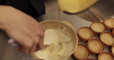 Bir pasta şefi tatlı karışımını bir kaseye koyar. Pasta yapma süreci yakın plan.