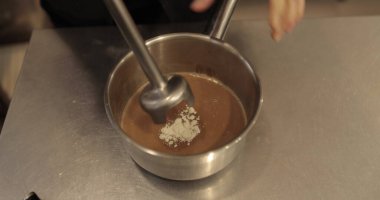 Kadın elleri, krema yaparken metal bir tencerede blender ile bileşenleri öğütüyor. Mutfakta yemek pişirmek.